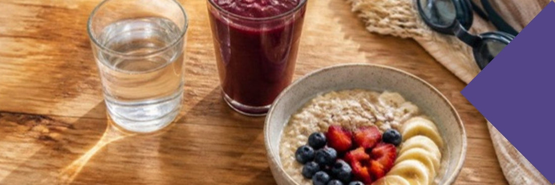 Water, a beetroot smoothie and oats with fruit on a sunny bench after a morning swim